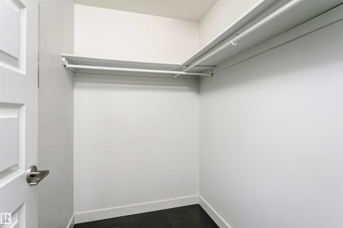 Walk-in closet with white walls, dark flooring, and built-in shelving - #1902 10388 105 St Nw, Edmonton, AB 