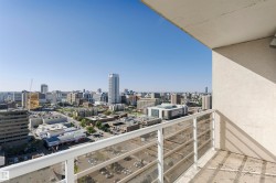 Expansive cityscape with multiple high-rise structures, featuring a balcony with a white metal railing and glass panels - 
