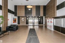 Lobby with neutral-toned tiled flooring, accent walls featuring dark and light-toned paneling, dual stainless steel elevators, and recessed lighting - 