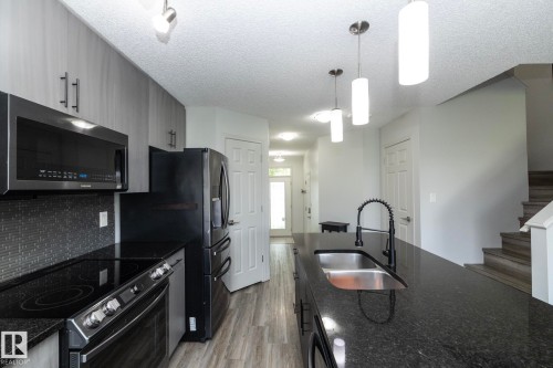 Kitchen with dark appliances, light wood-finish cabinetry, and dark countertops - 1640 Chapman Way Sw, Edmonton, AB - Indoor Photo Showing Kitchen With Double Sink With Upgraded Kitchen