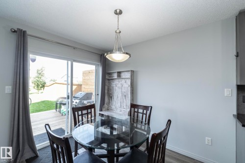 Dining area featuring a contemporary pendant light fixture, light gray wall paint, and wood-finish flooring - 1640 Chapman Way Sw, Edmonton, AB - Indoor Photo Showing Dining Room