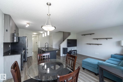 Open-concept living space featuring wood-finish flooring, a kitchen with dark cabinetry and countertops, and a central island with an integrated sink - 1640 Chapman Way Sw, Edmonton, AB - Indoor Photo Showing Dining Room