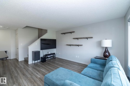Spacious living area featuring wood-finish flooring, light grey walls, and a staircase with a white railing - 1640 Chapman Way Sw, Edmonton, AB - Indoor Photo Showing Living Room