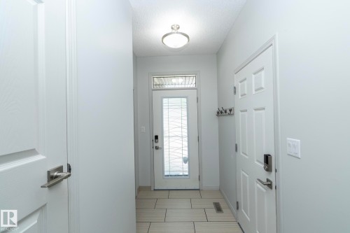 Entryway featuring light-toned tile flooring, a glass-panel front door with transom window, and a flush-mount ceiling light fixture - 1640 Chapman Way Sw, Edmonton, AB - Indoor Photo Showing Other Room