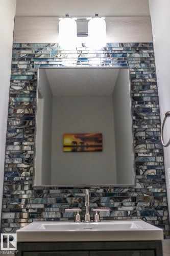 Vanity area featuring a rectangular mirror framed by iridescent blue and gray subway tile - 1640 Chapman Way Sw, Edmonton, AB - Indoor Photo Showing Other Room