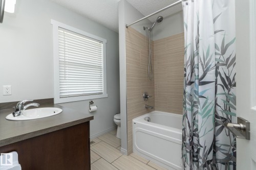 Bathroom featuring a single vanity with an integrated sink, dark wood-finish cabinetry, and a window with horizontal blinds - 1640 Chapman Way Sw, Edmonton, AB - Indoor Photo Showing Bathroom
