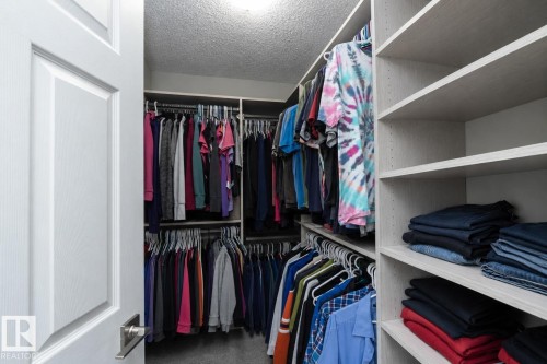Walk-in closet featuring custom shelving, multiple hanging rods, built-in organizers, and overhead lighting - 1640 Chapman Way Sw, Edmonton, AB - Indoor With Storage