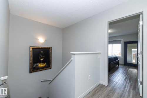 Upper level hallway featuring light gray wall paint, a built-in wall sconce, and wood-finish flooring - 1640 Chapman Way Sw, Edmonton, AB - Indoor Photo Showing Other Room