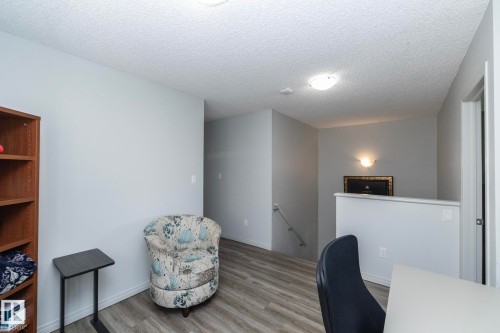 Upper-level landing featuring wood-finish flooring, light gray wall paint, a built-in wall sconce, and a partial view of a staircase with a handrail - 1640 Chapman Way Sw, Edmonton, AB - Indoor Photo Showing Office