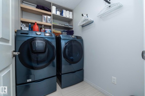 Dedicated laundry area featuring a washer and dryer with pedestal bases, integrated shelving, and light-toned walls - 1640 Chapman Way Sw, Edmonton, AB - Indoor Photo Showing Laundry Room