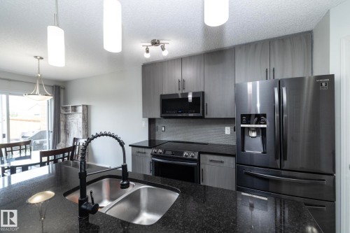 Kitchen featuring a dark granite island with dual stainless steel sinks and a matte black gooseneck faucet - 1640 Chapman Way Sw, Edmonton, AB - Indoor Photo Showing Kitchen With Double Sink With Upgraded Kitchen