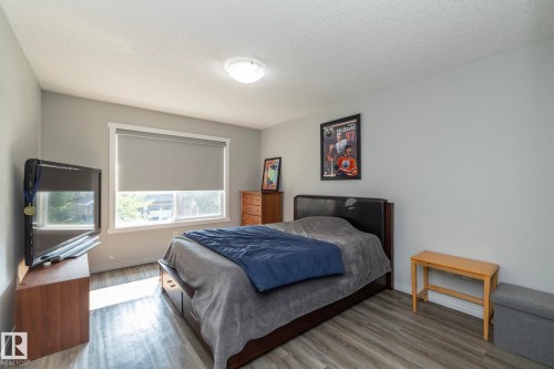 Room featuring wood-finish flooring, neutral wall tones, and a window with a roller shade - 1640 Chapman Way Sw, Edmonton, AB - Indoor Photo Showing Bedroom