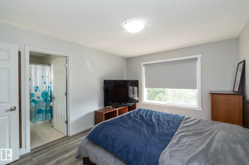 Bedroom featuring wood-finish flooring, a window with roller shade, and light gray walls - 1640 Chapman Way Sw, Edmonton, AB - Indoor Photo Showing Bedroom