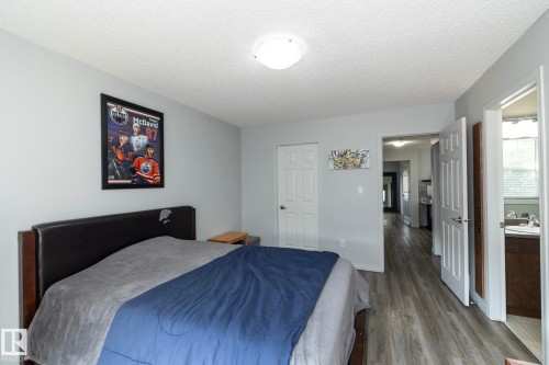 Bedroom featuring light gray walls, wood-finish flooring, a white paneled door, and a flush mount ceiling light - 1640 Chapman Way Sw, Edmonton, AB - Indoor Photo Showing Bedroom