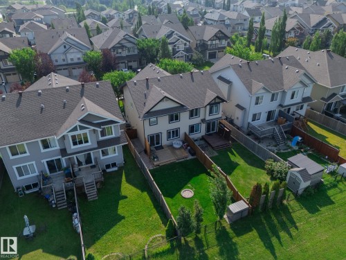 Private fenced backyard featuring a large elevated deck, mature landscaping, and a storage shed - 1640 Chapman Way Sw, Edmonton, AB - Outdoor With Facade