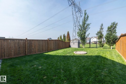 Expansive backyard featuring a lush lawn, privacy fencing, and a built-in fire pit - 1640 Chapman Way Sw, Edmonton, AB - Outdoor