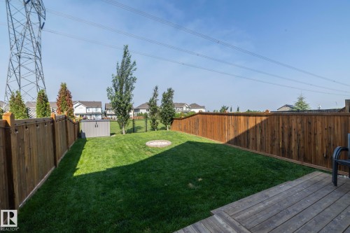 Expansive backyard featuring a manicured lawn, a built-in fire pit, and a wooden privacy fence - 1640 Chapman Way Sw, Edmonton, AB - Outdoor With Backyard