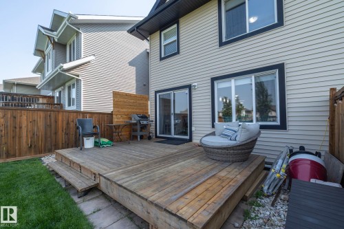Spacious wood deck with multi-level design, featuring direct access via a glass sliding door, surrounded by a wooden privacy fence, and bordered by a manicured lawn - 1640 Chapman Way Sw, Edmonton, AB - Outdoor With Deck Patio Veranda With Exterior