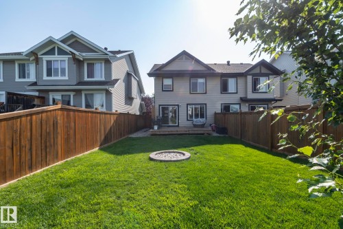 Expansive grassy backyard featuring a built-in fire pit, a wooden deck, and a privacy fence - 1640 Chapman Way Sw, Edmonton, AB - Outdoor