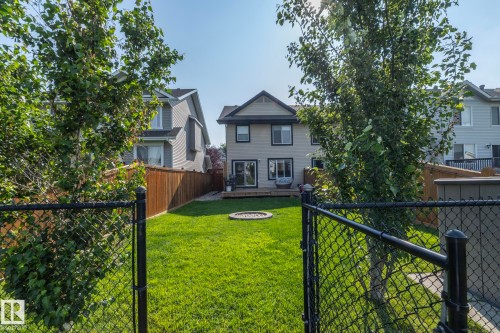 Private fenced backyard featuring a wooden deck, fire pit, and ample green space - 1640 Chapman Way Sw, Edmonton, AB - Outdoor
