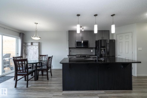 Kitchen featuring a large island with dark countertops, matte black appliances, and grey cabinetry - 1640 Chapman Way Sw, Edmonton, AB - Indoor