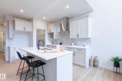 Kitchen with light wood-finish flooring, white cabinetry, integrated stainless steel range hood, light subway tile backsplash, and a central island with an undermount sink - 