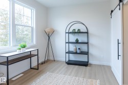 Light wood-finish flooring, white walls, and a white sliding barn door with matte black hardware - 