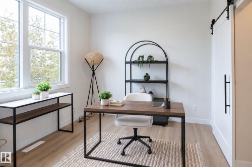 Wood-finish flooring, white walls, and a white barn-style door with black hardware - 6306 65 Ave, Beaumont, AB 