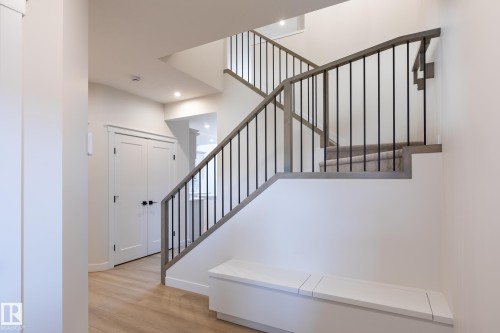 Wood-finish flooring, two-panel interior doors, contemporary staircase with wood handrail and black balusters, recessed lighting, and built-in storage bench - 6306 65 Ave, Beaumont, AB 