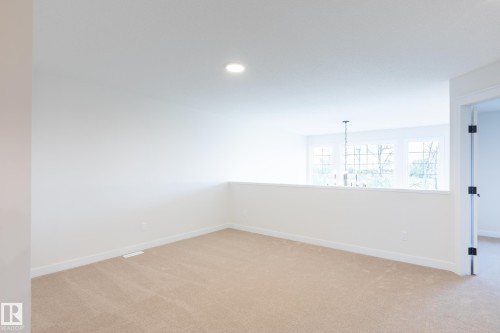Carpeted room with a half-wall partition and recessed lighting - 6306 65 Ave, Beaumont, AB 
