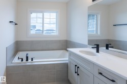 Built-in tub with matte black fixtures, framed window, and a tile surround - 