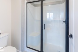 Walk-in shower with clear glass enclosure and matte black framing - 