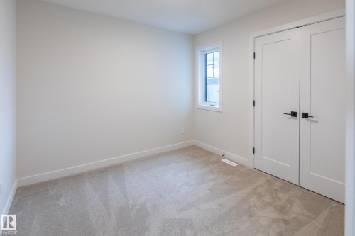 Light-toned carpeted flooring, white walls, and a window with white trim - 6306 65 Ave, Beaumont, AB 