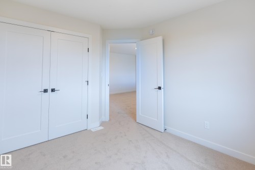 Neutral wall tones, carpeted flooring, two-panel interior doors, and matte black hardware - 6306 65 Ave, Beaumont, AB 