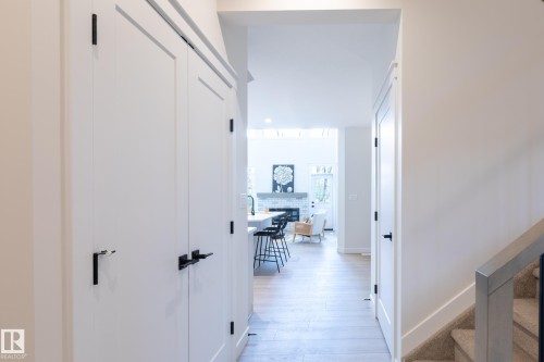 White paneled doors with matte black hardware, wood-finish flooring, and a carpeted staircase with a metal railing - 6306 65 Ave, Beaumont, AB 