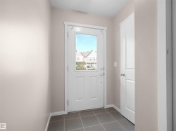 Entryway featuring a white paneled door with an integrated window, dark gray square tile flooring, and light neutral painted walls - 
