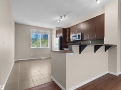 Kitchen with dark wood cabinetry, stainless steel microwave, and an extended breakfast bar - 