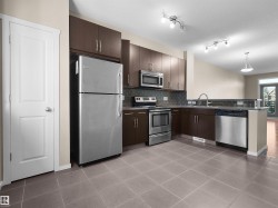 Kitchen featuring stainless steel appliances, dark wood-finish cabinetry, tile flooring, and track lighting - 