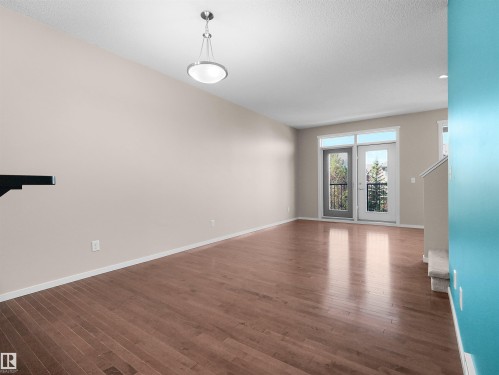 Hardwood-style flooring throughout, neutral wall paint, and a modern ceiling light fixture - #162 603 Watt Bv Sw, Edmonton, AB 