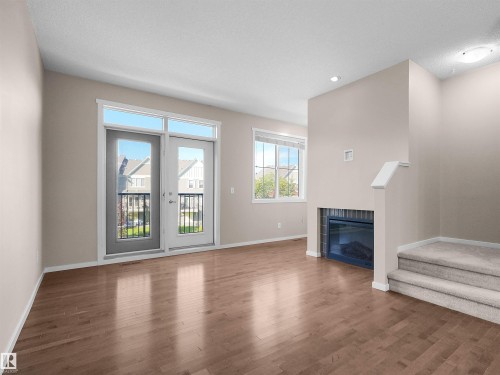 Hardwood-finish flooring, built-in fireplace with tile surround, French doors leading to a balcony, multiple windows for natural light, and recessed ceiling lighting - #162 603 Watt Bv Sw, Edmonton, AB 