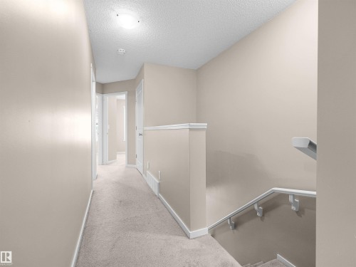 Carpeted hallway with light neutral wall paint and white trim - #162 603 Watt Bv Sw, Edmonton, AB 