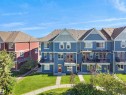 Townhome exterior featuring blue horizontal siding, white trim, multiple balconies with black railings, and a peaked roofline - #162 603 Watt Bv Sw, Edmonton, AB 