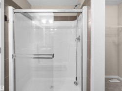 Shower enclosure with sliding glass door, chrome hardware, and a built-in shelf - 
