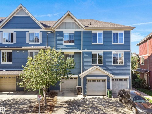 Blue siding exterior with white window trim, multiple windows, and two attached garages - #162 603 Watt Bv Sw, Edmonton, AB 