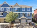 Blue siding exterior with white window trim, multiple windows, and two attached garages - #162 603 Watt Bv Sw, Edmonton, AB 