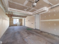 Window with natural light, concrete flooring, overhead garage door mechanism, and interior access door - 