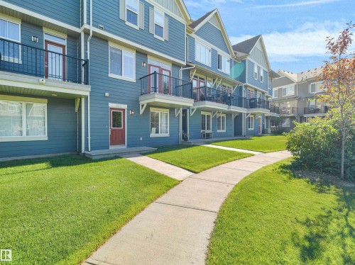 Blue multi-story building with gabled roofline, multiple balconies with black railings, and a concrete walkway - #162 603 Watt Bv Sw, Edmonton, AB 