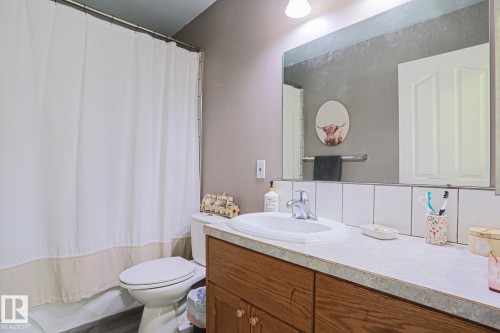Bathroom featuring a built-in wood-finish vanity with a laminate countertop, ceramic sink, and chrome faucet - 21 Burlington Avenue, Spruce Grove, AB 