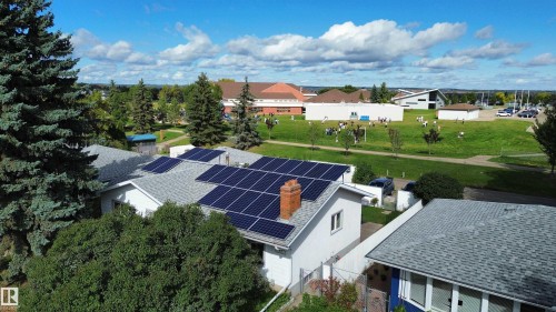 Solar panel system installed on a shingled roof, featuring a brick chimney - 21 Burlington Avenue, Spruce Grove, AB 