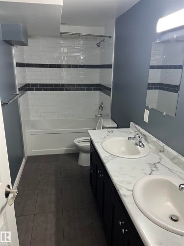 Dual vanity with white undermount sinks, a marble-patterned countertop, and dark cabinetry - 21 Burlington Avenue, Spruce Grove, AB 
